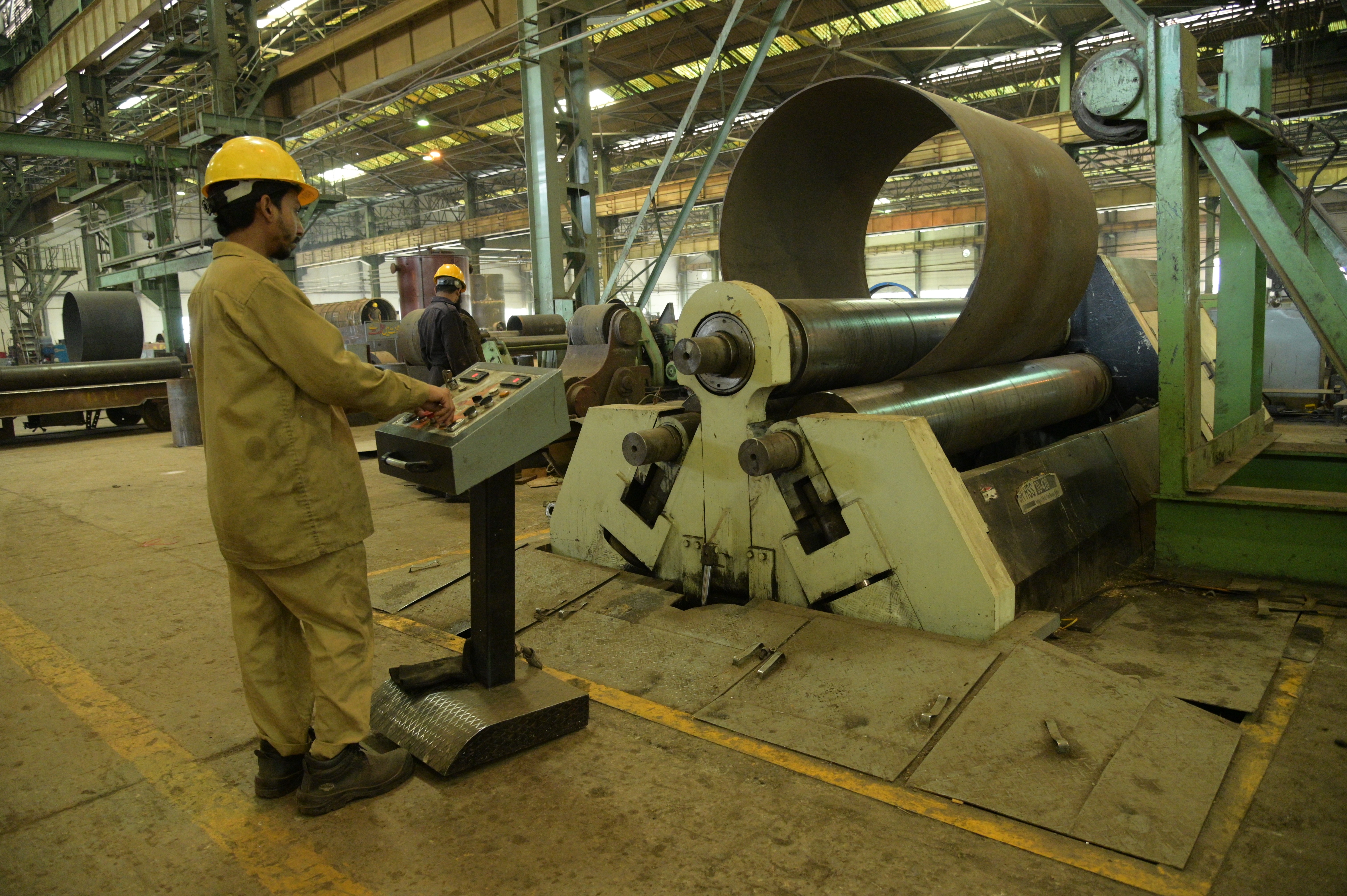 A worker using a machine to make the thickness of cylinder even