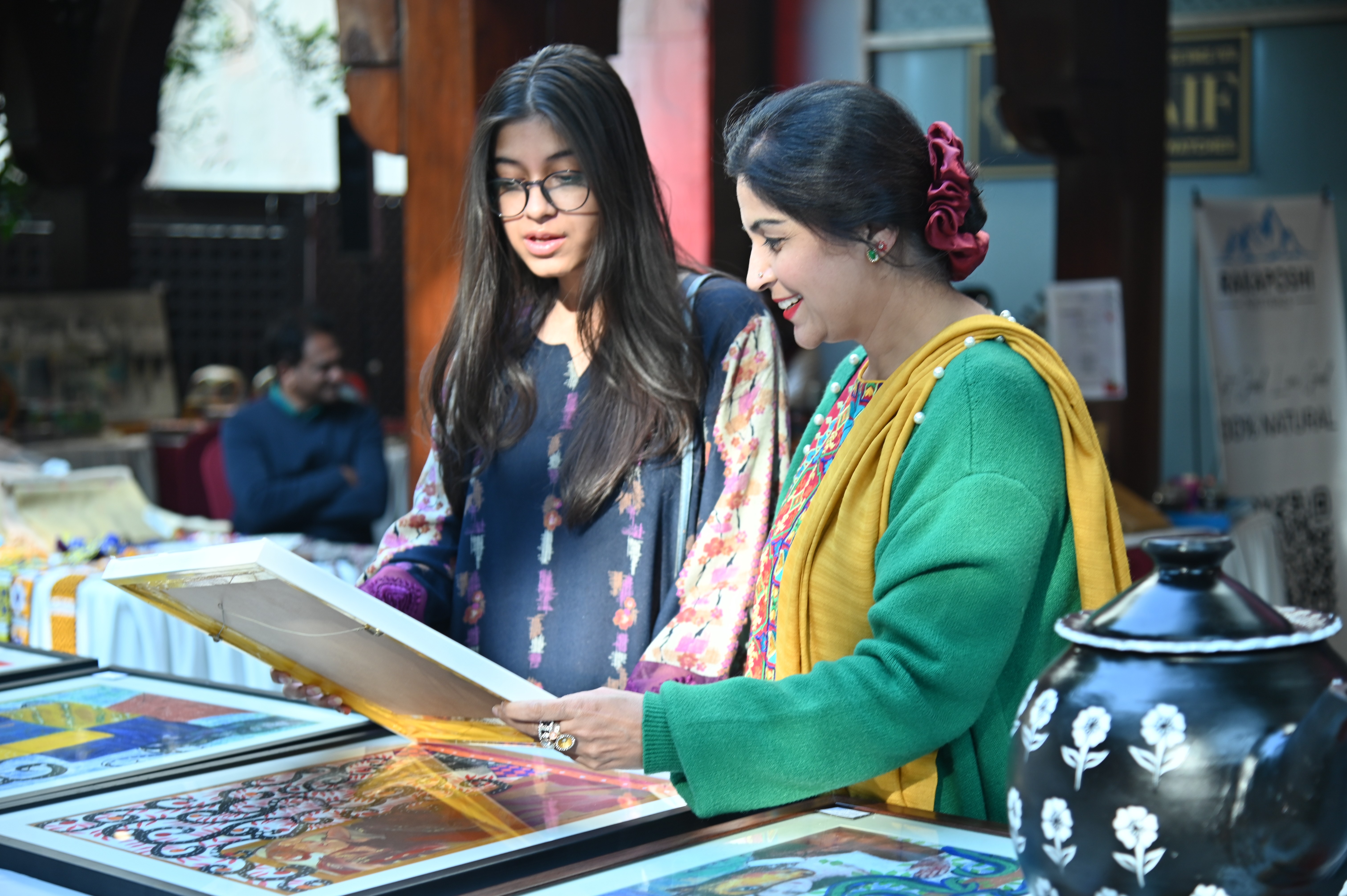 Two women looking at the hand made embroidered frames