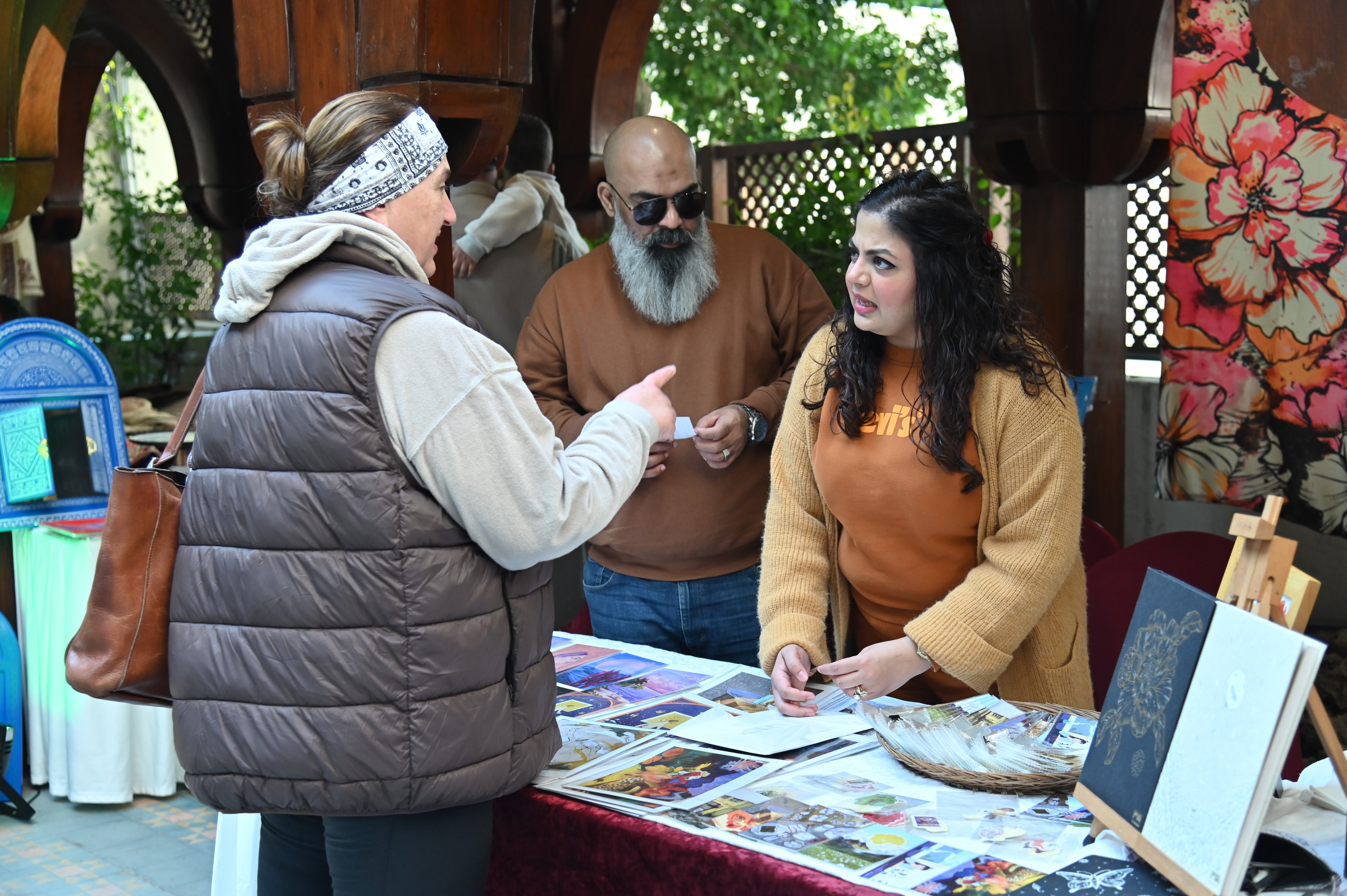 A girl having a stall of colorful paintings briefing the foreign visitor