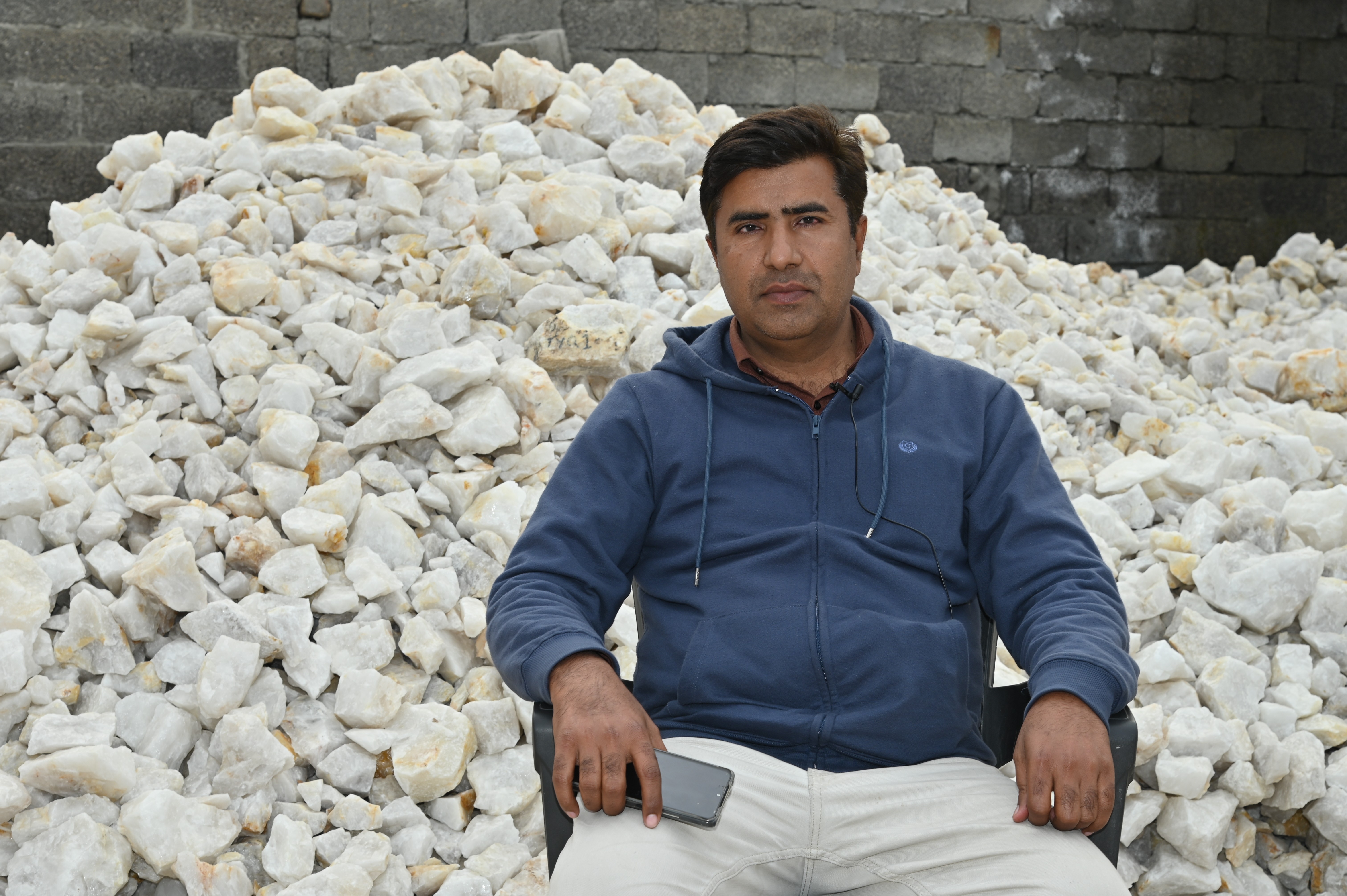 A man sitting infront of the Industrial Mineral named Silica Quartz mainly used in the manufacture of many optical parts such as lenses, mirrors, UV, IR transmitting optics, and metrology com