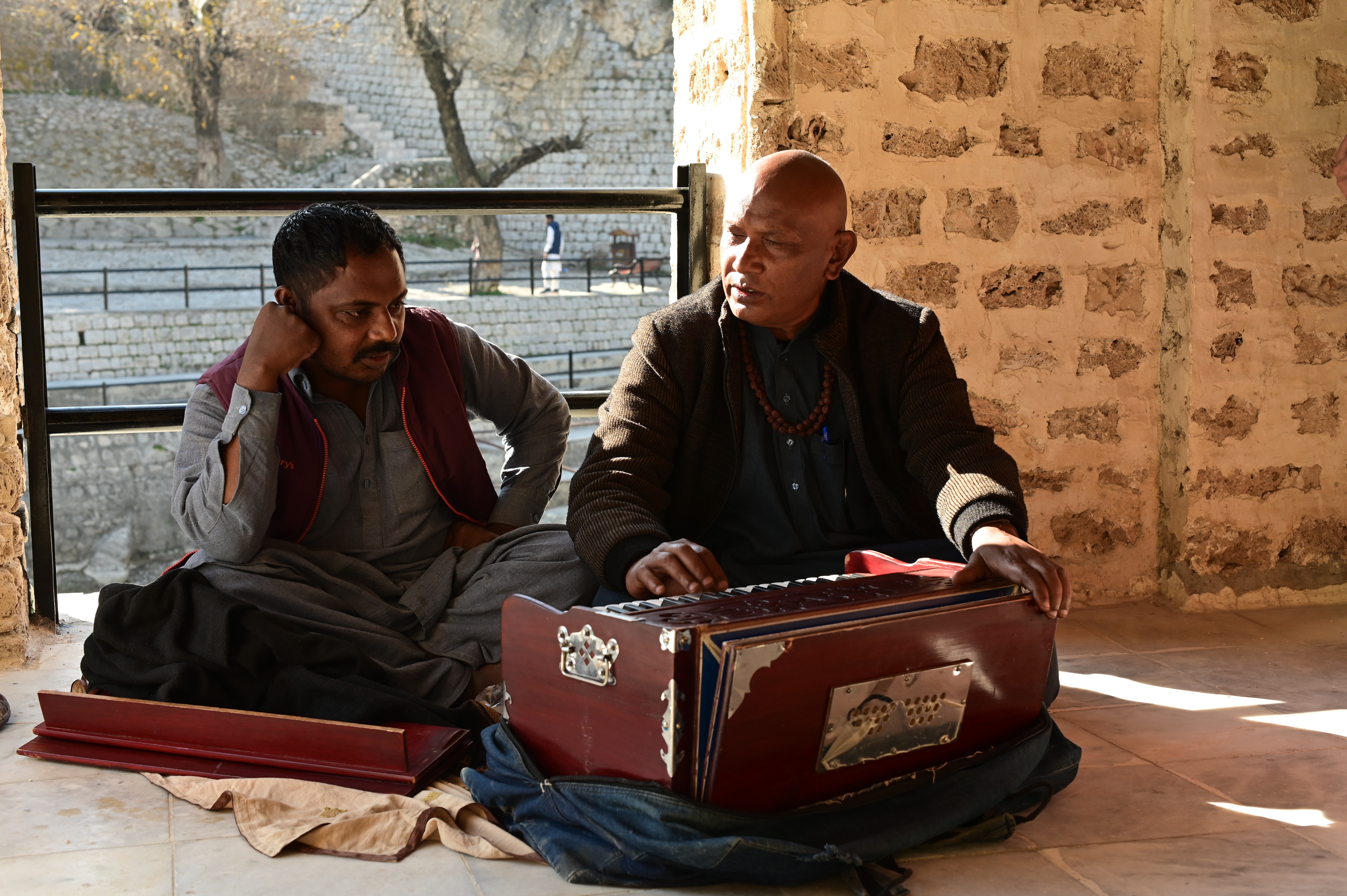 A men playing Harmonium, an instrument that makes sound by blowing air through reeds, which are tuned to different pitches to make musical notes.