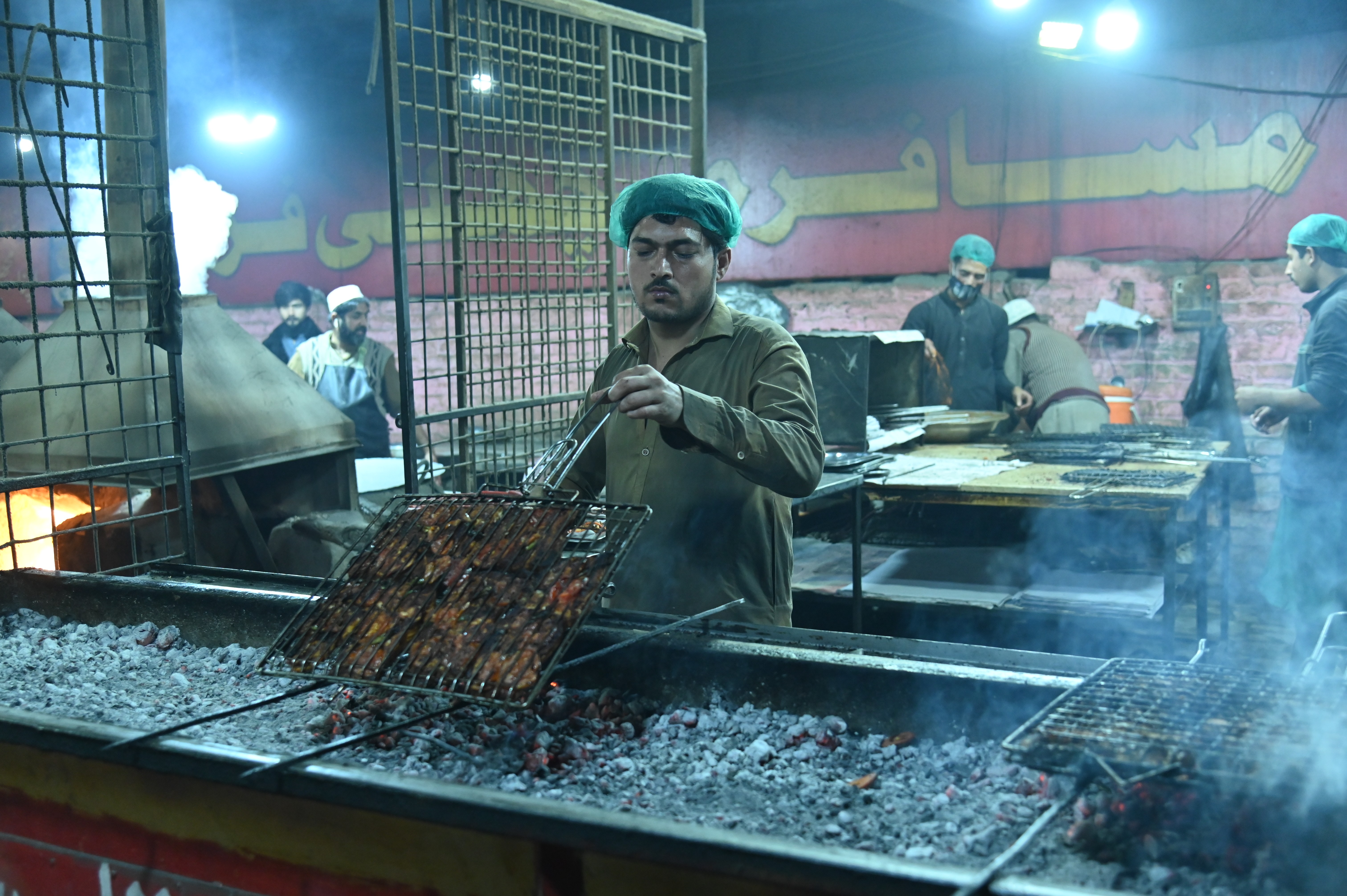 A man making grilled fish over low medium coal flames