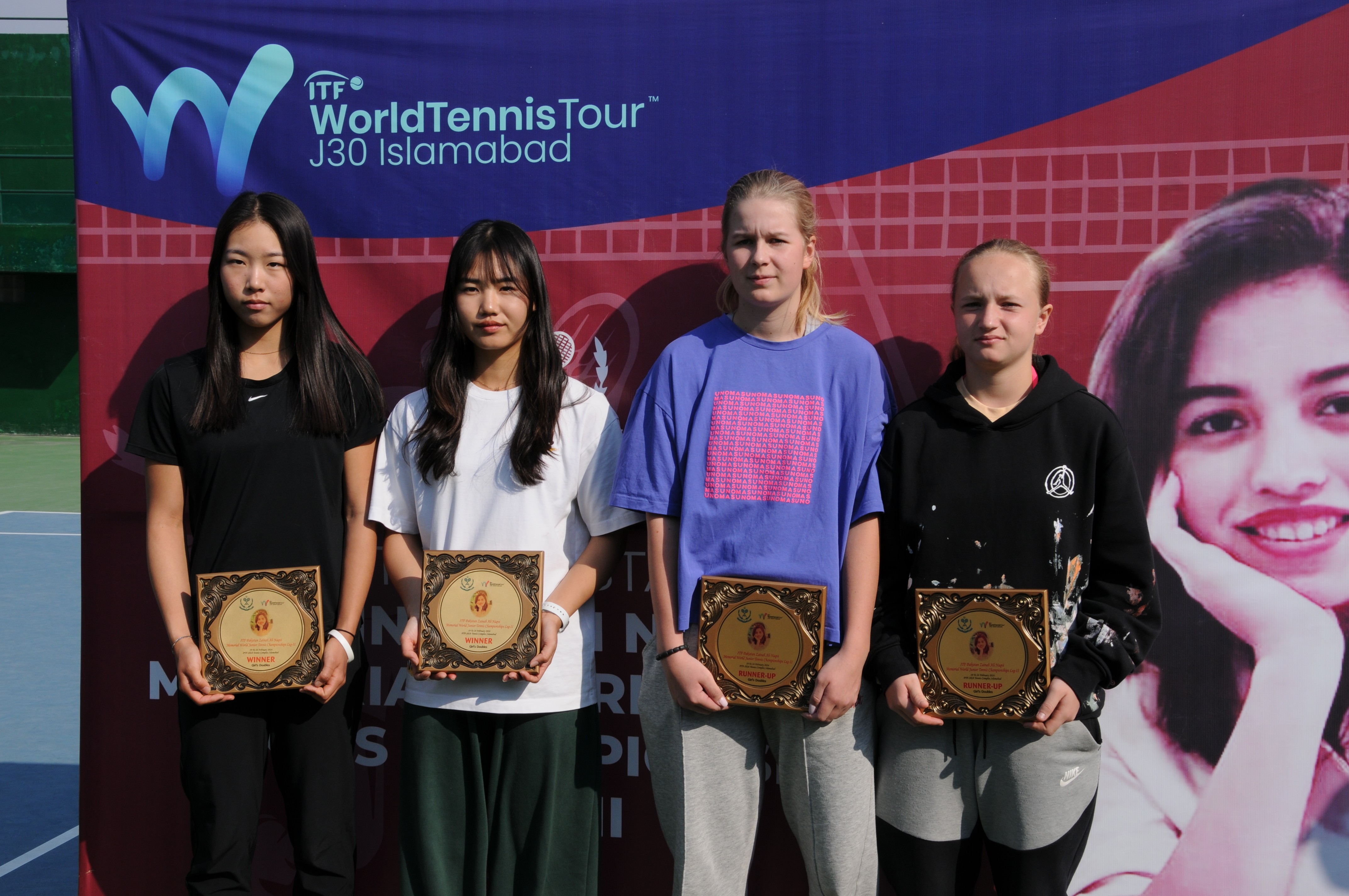 Tennis players posing with their winning trophy