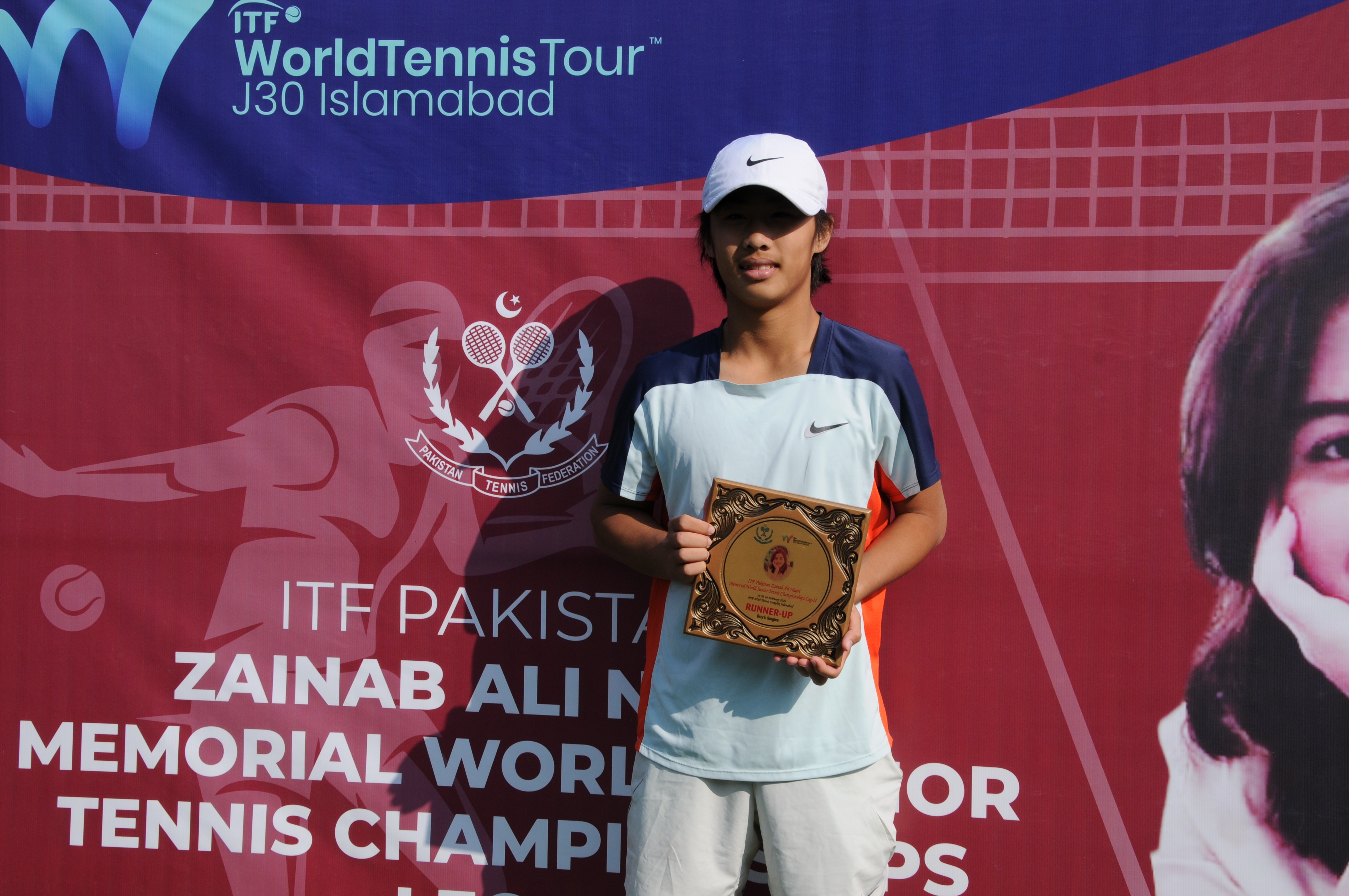 A winning tennis player posing with his trophy